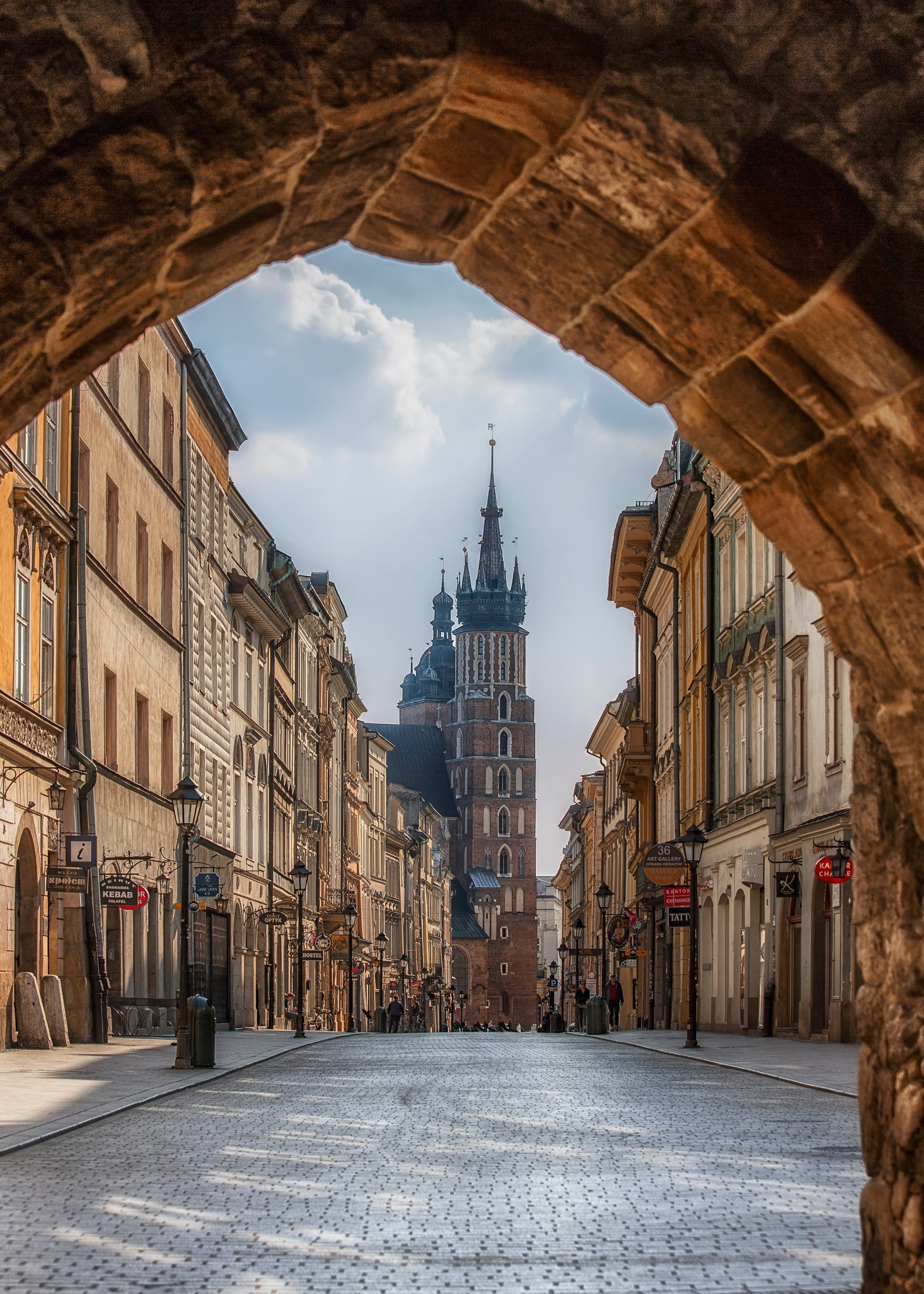Floriańska Street with St. Mary's Basilica tower framed by historic archway, Kraków Old Town